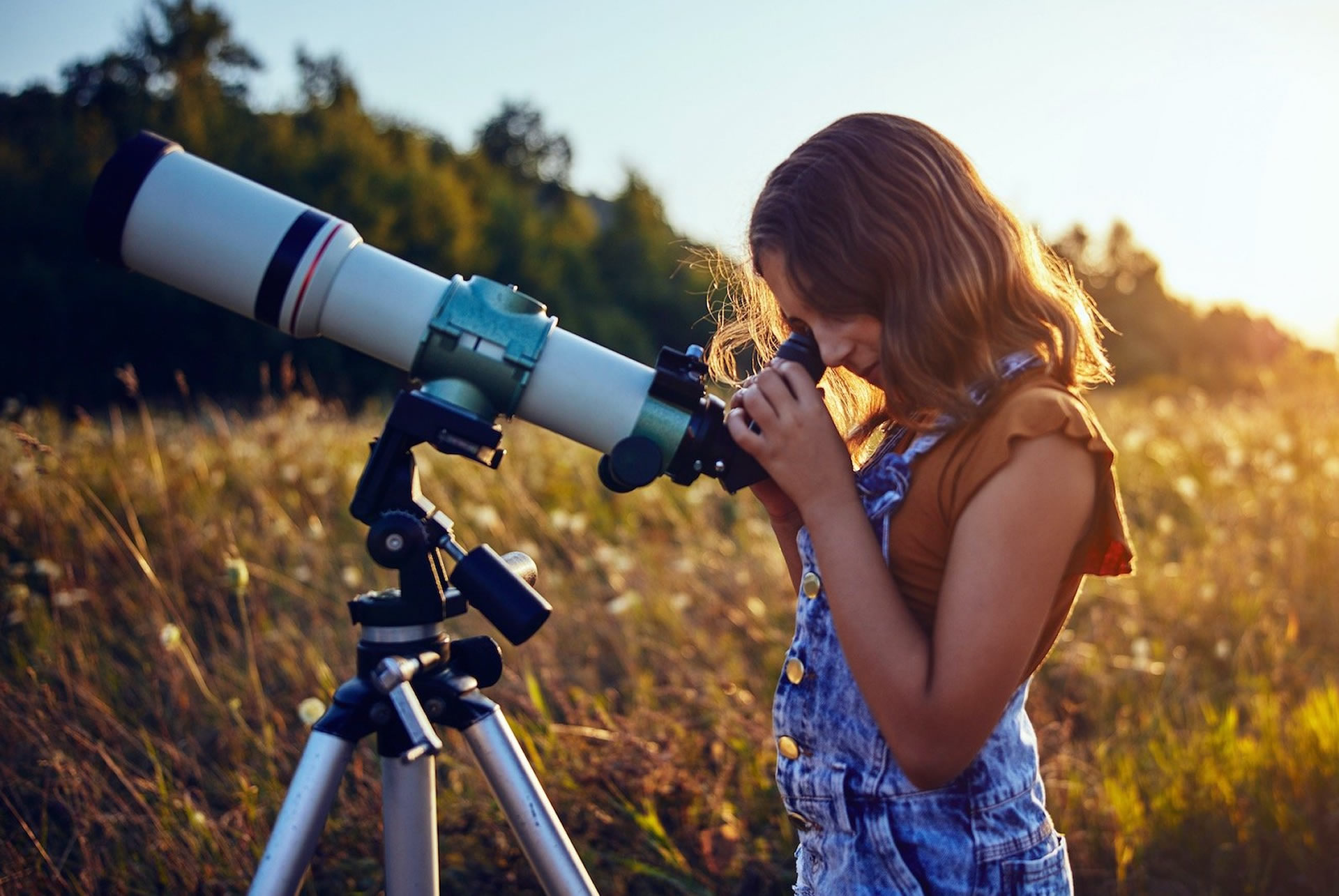 Niña, campo, cielo abierto y telescopio